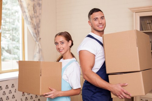 Removal professionals carrying items through a Kensington flat staircase